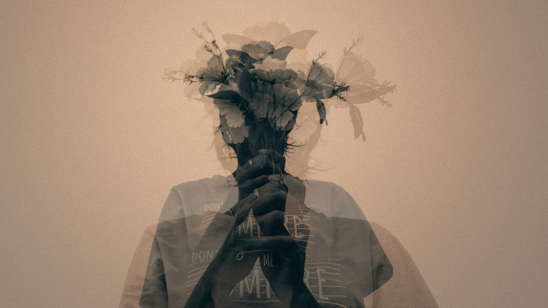Double-exposure portrait of a person holding flowers, face obscured