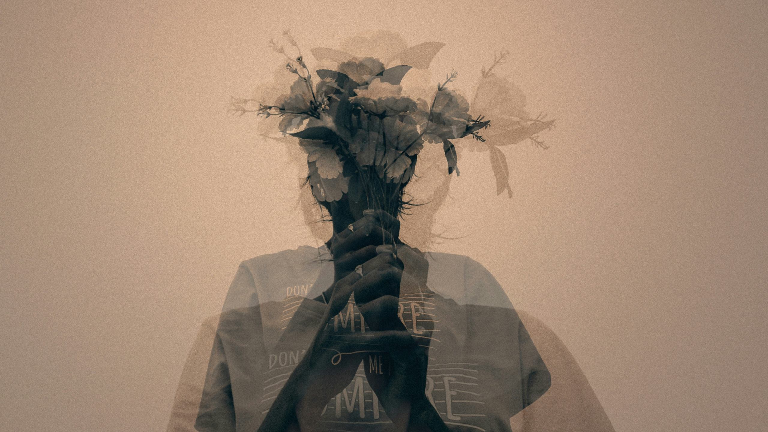 Double-exposure portrait of a person holding flowers, face obscured
